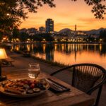 A quiet outdoor table at Zgara Korçare on the edge of Liqeni Artificial in Tirana at dusk, warm amber light, simple grilled meal