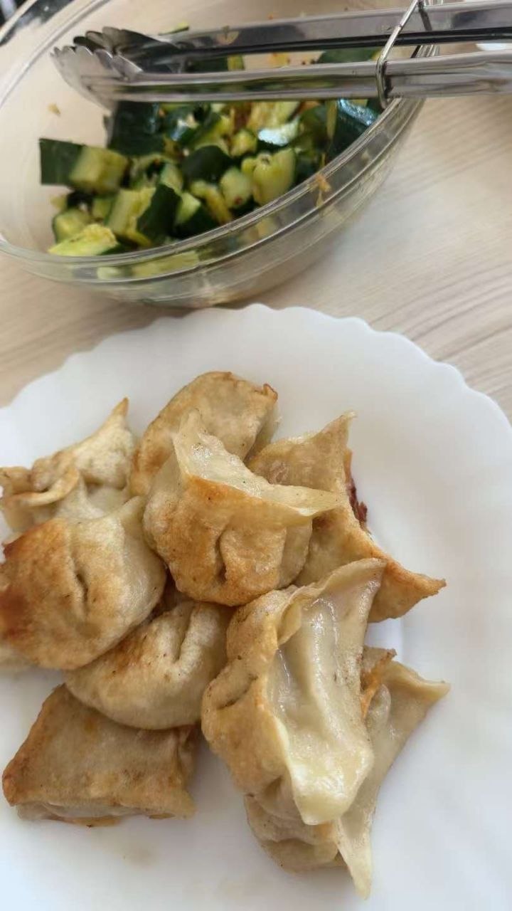 A floured board, resting dumpling dough, black vinegar, chilli oil, and a steaming pot in a warm Tirana kitchen at dusk