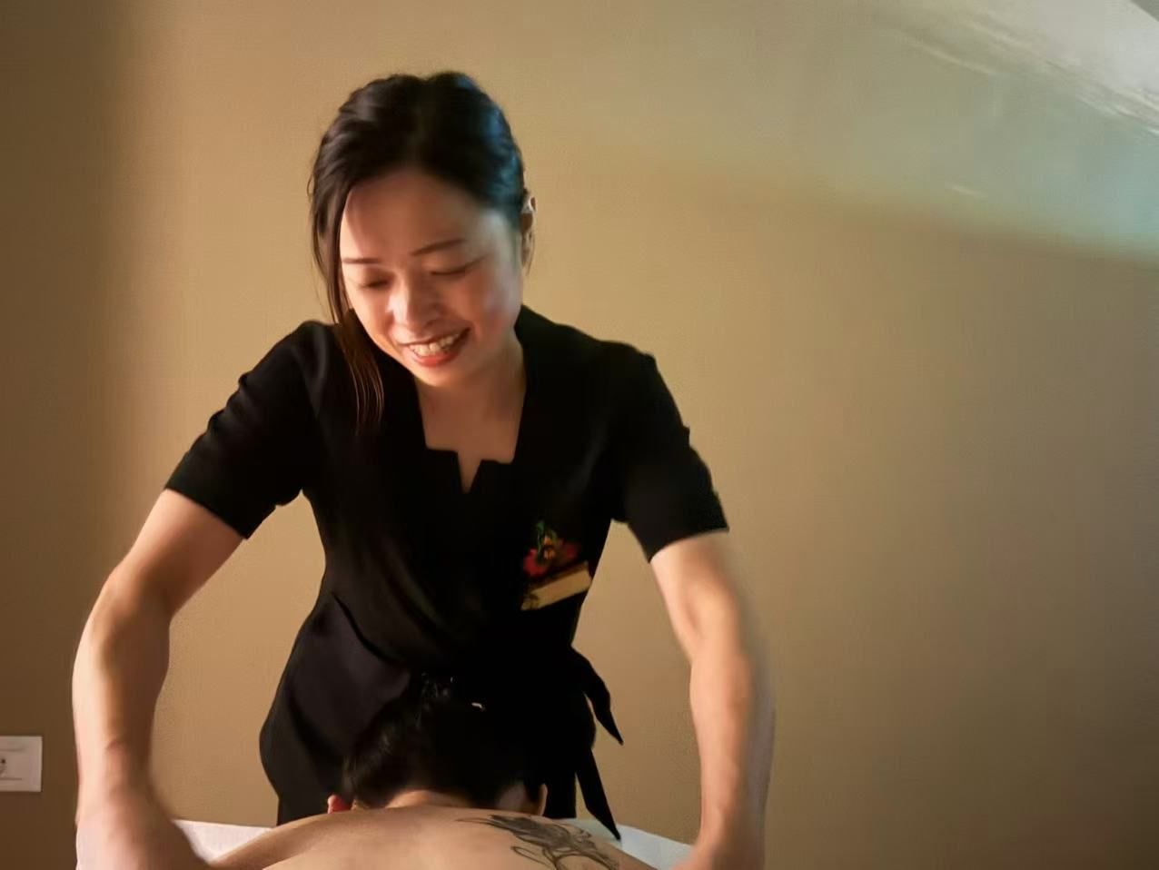 A tray with a folded white towel, warm oil and a teapot in a cosy massage parlour